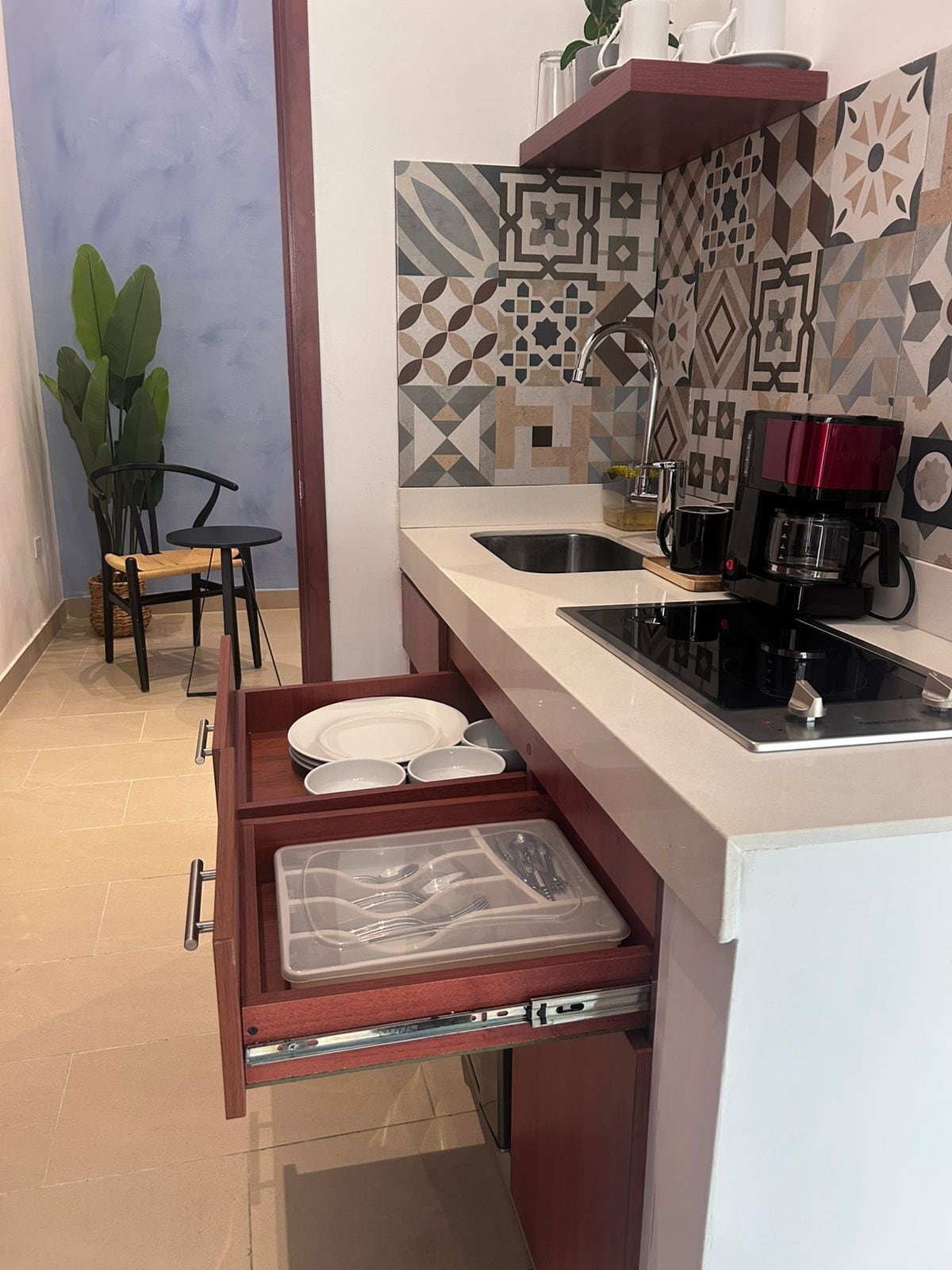 A compact kitchen with a built-in sink, a coffee maker, and a drawer organizer.