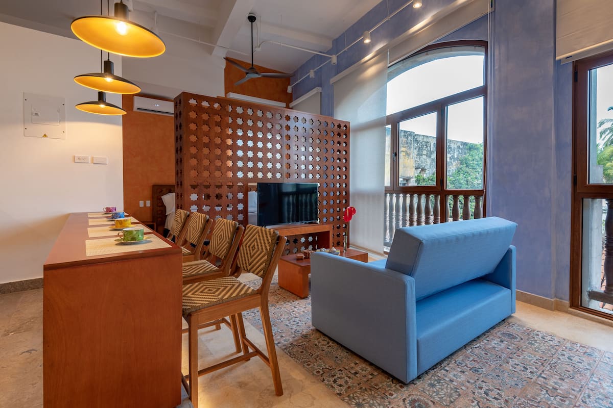 A modern living room with a TV, blue sofa, wooden coffee table, and a decorative partition.
