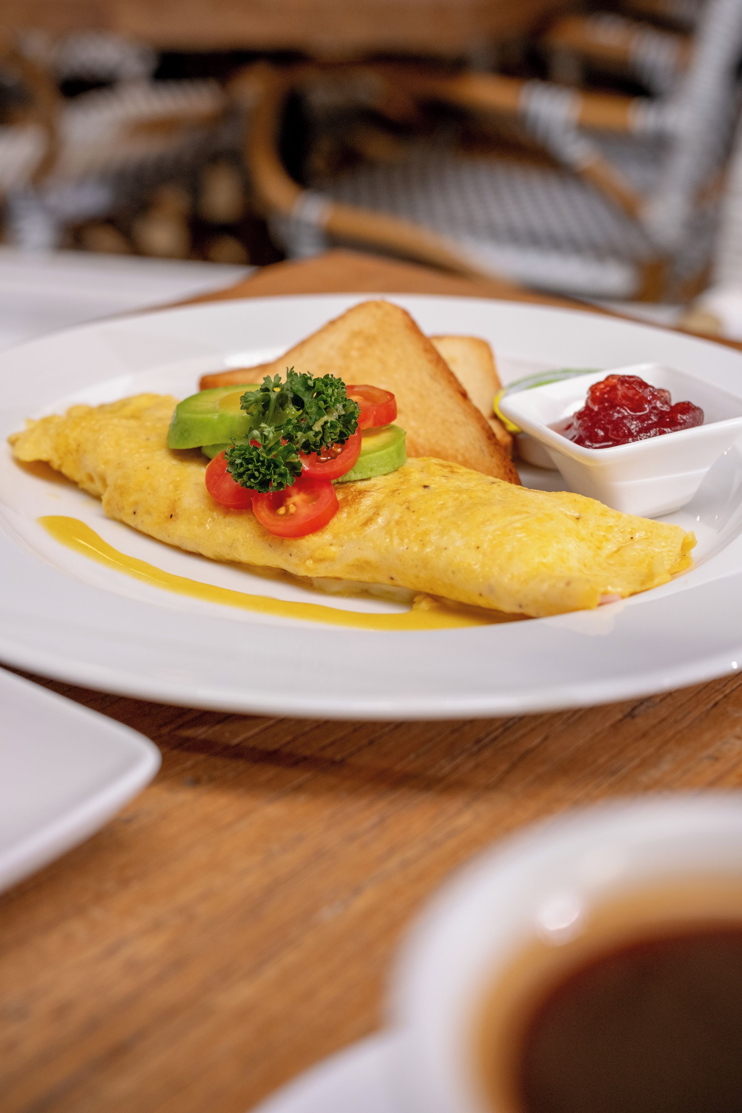 Une assiette avec une omelette, des toasts et un petit bol de confiture.