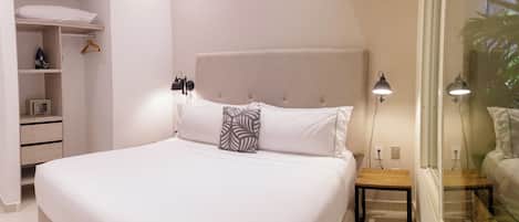 Una cama bien hecha con cabecera, mesitas de noche y una lámpara colgante.