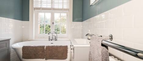 Ein Badezimmer mit Badewanne, Toilette und einem Fenster mit Jalousien.