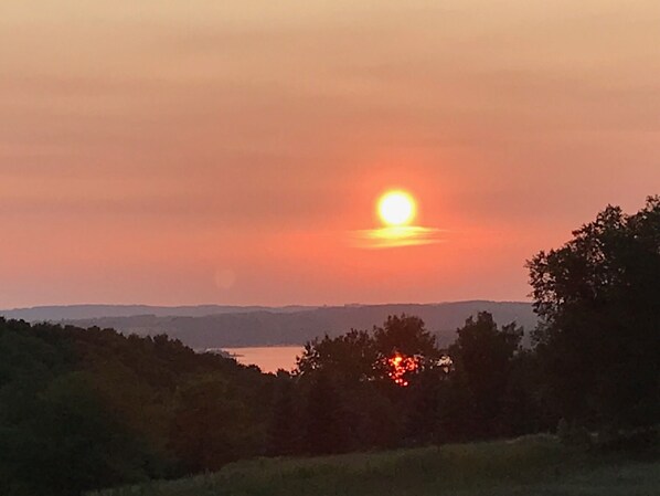 Ein Sonnenuntergang über einem Gewässer, im Vordergrund Bäume.