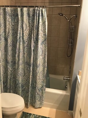 Ein Badezimmer mit Dusche, Toilette und einem duschigen Vorhang mit Muster.