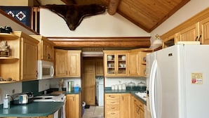Une cuisine avec des meubles de rangement en bois, un réfrigérateur blanc, un four à micro-ondes et une cuisinière.