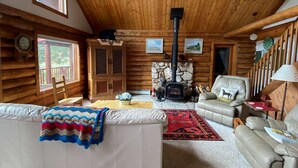 L’intérieur d’un chalet confortable, avec une cheminée, des canapés en cuir, un plafond en bois et un coin repas.