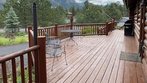 Une terrasse en bois avec une table et des chaises, offrant une vue sur un paysage montagneux.