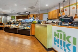 Balcão de pastelaria com vitrine, caixa registradora e balcão com logotipo.