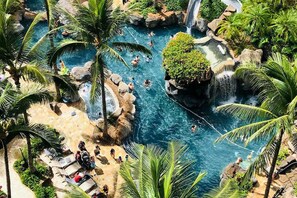 Um resort tropical com várias piscinas, palmeiras e uma cascata.