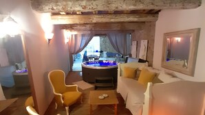 Un espace salon accueillant avec un plancher en bois, des fauteuils jaunes, un canapé blanc et un jacuzzi en arrière-plan.