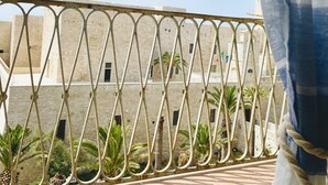 A balcony with a metal railing, a tiled floor, and a building in the background.