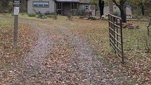 A private property with a house, a fenced yard, and autumn foliage.