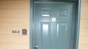 A door with a number plate '563' and a sign prohibiting BBQs and smoking.