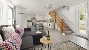 Uma sala de estar moderna com um sofá, uma mesa de jantar e uma escada.