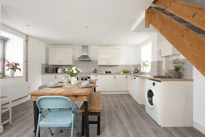 A modern kitchen with white cabinets, a wooden dining table, and a built-in washing machine.