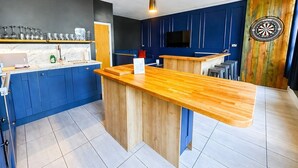Una cocina moderna con armarios azules, una isla de madera y un dardo en la pared.