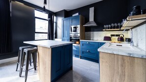 Una cocina moderna con armarios azules, encimera de mármol y horno empotrado.