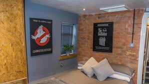 Un dormitorio con una cama, una pared de ladrillo, un cartel de Cazafantasmas y un cartel de El Halcón Maltés.