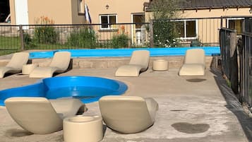 Una piscina al aire libre, sillones reclinables de piscina