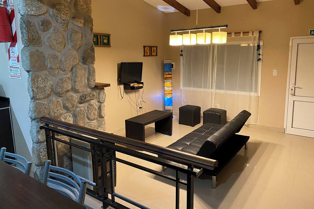 A living room with a stone wall, a black sofa, a TV, and a fireplace.
