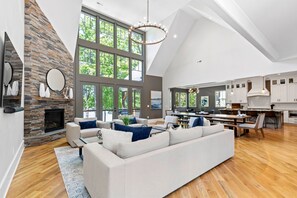 Relax in the spacious living area with a comfortable seating area, stone fireplace, and large windows offering views of the surrounding greenery.