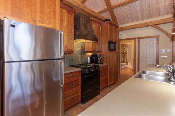 A kitchen with wooden cabinets, stainless steel appliances, and a tiled backsplash. - Lakefront Tie Lake l Hot Tub l Pool Table l A/C (Jaffray)