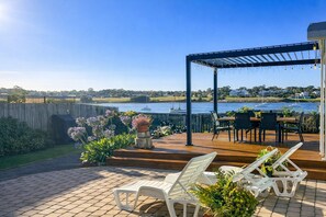 A wooden deck with outdoor furniture, a pergola, and a view of a body of water with boats. - Lux. Waterfront Cottage, Amazing Water Views /Fire Pit /Central/5km-MTB & Beach (George Town)