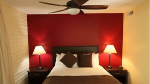 A hotel room with a red accent wall, a ceiling fan, two bedside lamps, and a bed with brown bedding. - The North Lake Lodges & Villas is a quaint boutique resort. Studio and sleeps 2 (Incline Village)