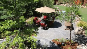 An outdoor patio with a table and chairs, surrounded by greenery and a small wooden structure. - The North Lake Lodges & Villas is a quaint boutique resort. Studio and sleeps 2 (Incline Village)