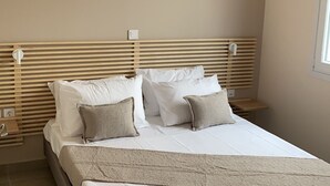 A bedroom with a bed, bedside tables, an air conditioning unit, and a wall-mounted decor piece. - Deatached apartment with shared pool in Tersanas Chania 2 minutes from the beach (Chorafakia)