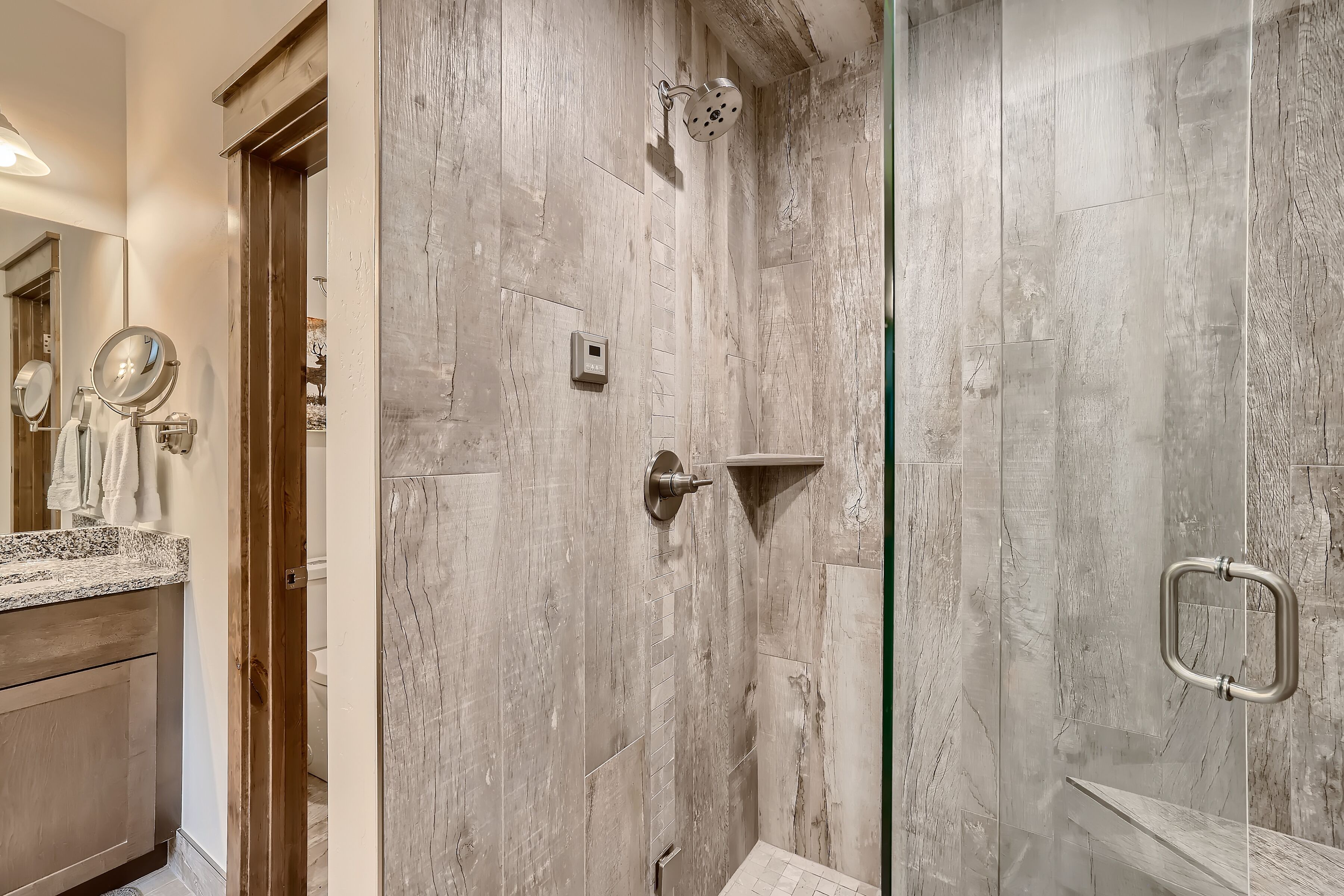 A bathroom with a shower, a vanity with a mirror, and a towel rack.