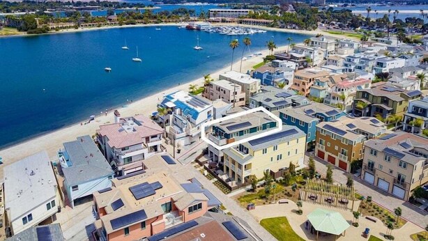 Zona residencial costera con casas modernas, un puerto deportivo y una playa.