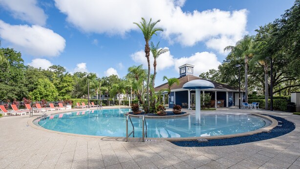 Une piscine circulaire entourée d’une terrasse, de chaises longues et d’un belvédère.
