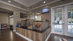 Un espace d’accueil avec un comptoir en bois, une machine à café et un téléviseur fixé au mur.