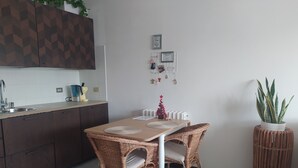 Moderni keittiö, jossa on ruokailutila, keittiösaareke, pesuallas ja ruukussa oleva kasvi.