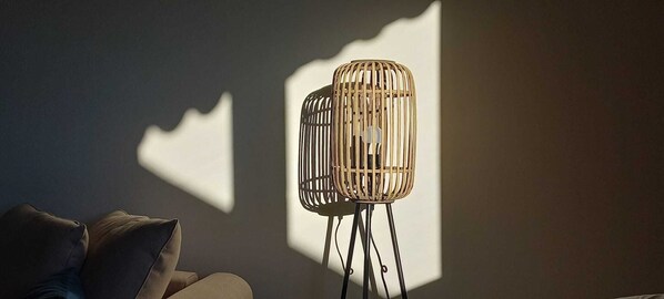 Um quarto com uma luminária moderna e uma sombra na parede.