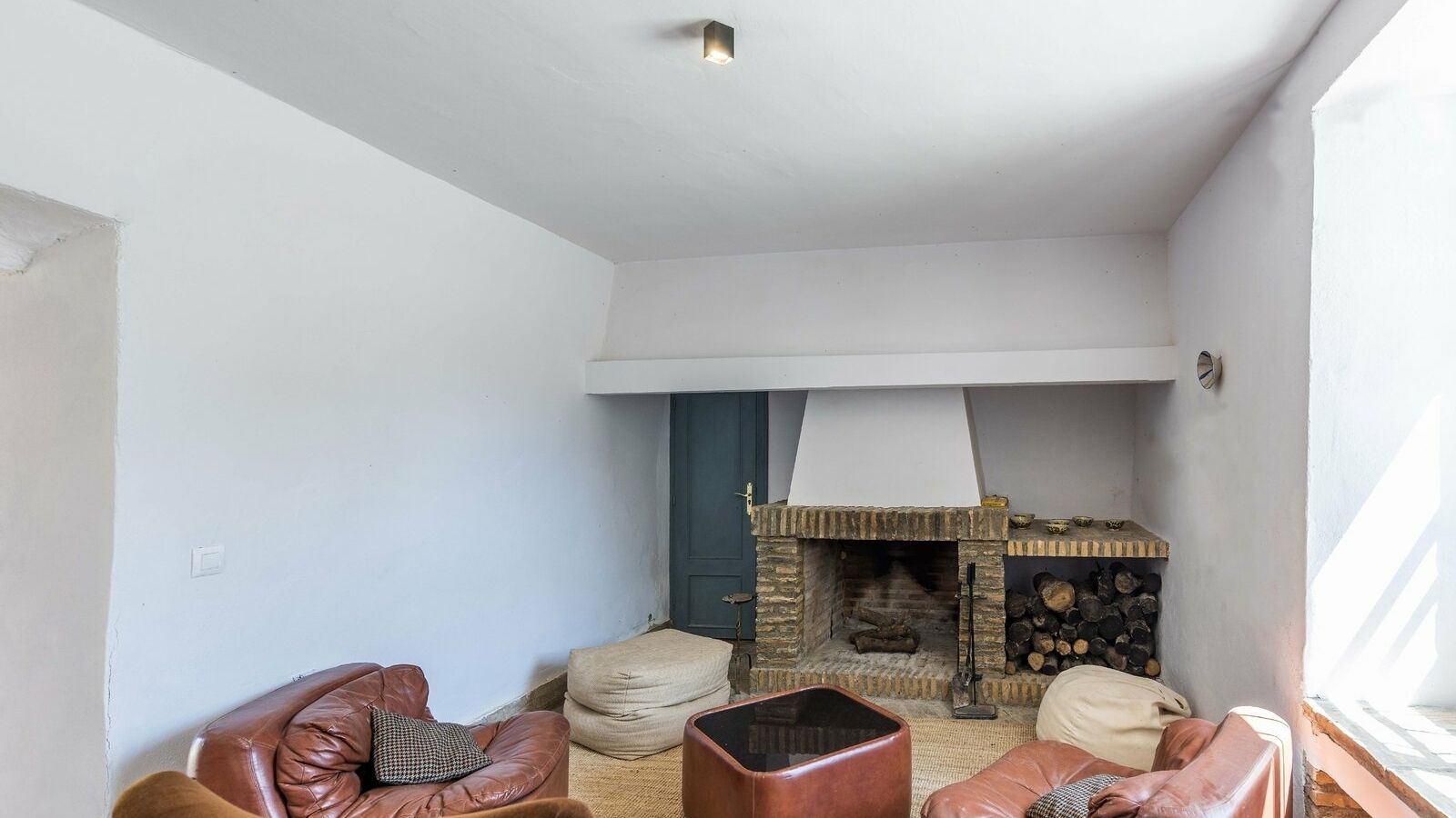 Ein Wohnzimmer mit Kamin aus Stein, Ledersofas und einem Fenster.