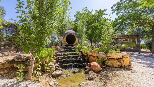 Un élément décoratif aquatique d’inspiration naturelle, comprenant une cascade en pierre et une grande structure tubulaire.