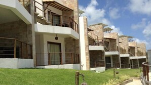 A modern building with multiple balconies and a well-maintained lawn. - Flat no Condomínio Brisas do Amor (RN)