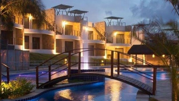 A hotel with a swimming pool, a bridge, and a waterfall. - Flat no Condomínio Brisas do Amor (RN)