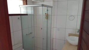 A bathroom with a glass-enclosed shower, a toilet, and a sink with a beige countertop. - Flat no Condomínio Brisas do Amor (RN)