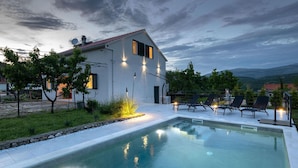 Une maison moderne dotée d’une piscine, d’un espace salon extérieur et offrant une vue sur les montagnes.