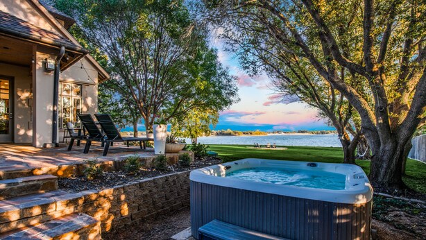 A hot tub in a backyard with a view of the water and trees. - Luxury Lakefront Estate - 1.6 Acres - Sleeps 12 - Boathouse + Sunset Views (Little Elm)