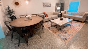 Un salón amplio con una mesa redonda de madera para comer, dos sofás, una mesita de centro y una alfombra estampada.