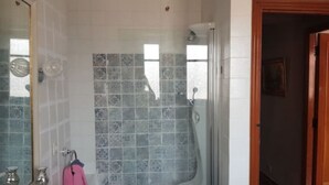 Un baño con ducha, espejo y toallero.