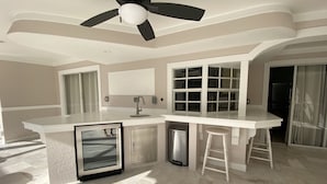 A modern kitchen with a large island, built-in appliances, and a ceiling fan. - EASY 5-Min Walk to Beach Path! NEW Saltwater Pool & Spa, Steps to Dining & Shops (Marco Island)