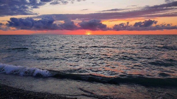 A sunset over the ocean with waves approaching the shore. - Fish ,Relax, Repeat.  (Conneaut)