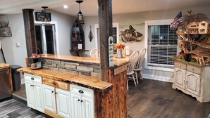 A kitchen with a wooden island, white cabinets, and a dining area with chairs. - Fish ,Relax, Repeat.  (Conneaut)