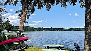 A lakeside picnic area with benches and a canoe.