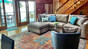 A cozy living room with a sectional sofa, a coffee table, and a staircase.