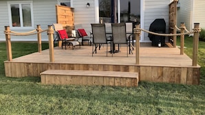 A deck with outdoor furniture, a barbecue grill, and a wooden fence.